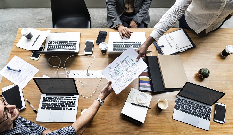 Stock image of collaboration. Person handing document to another