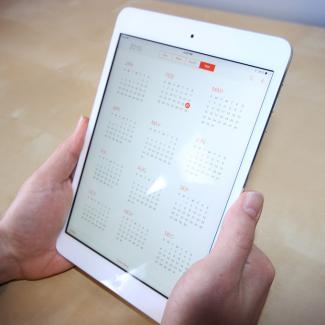 iPad held by hands with calendar app open